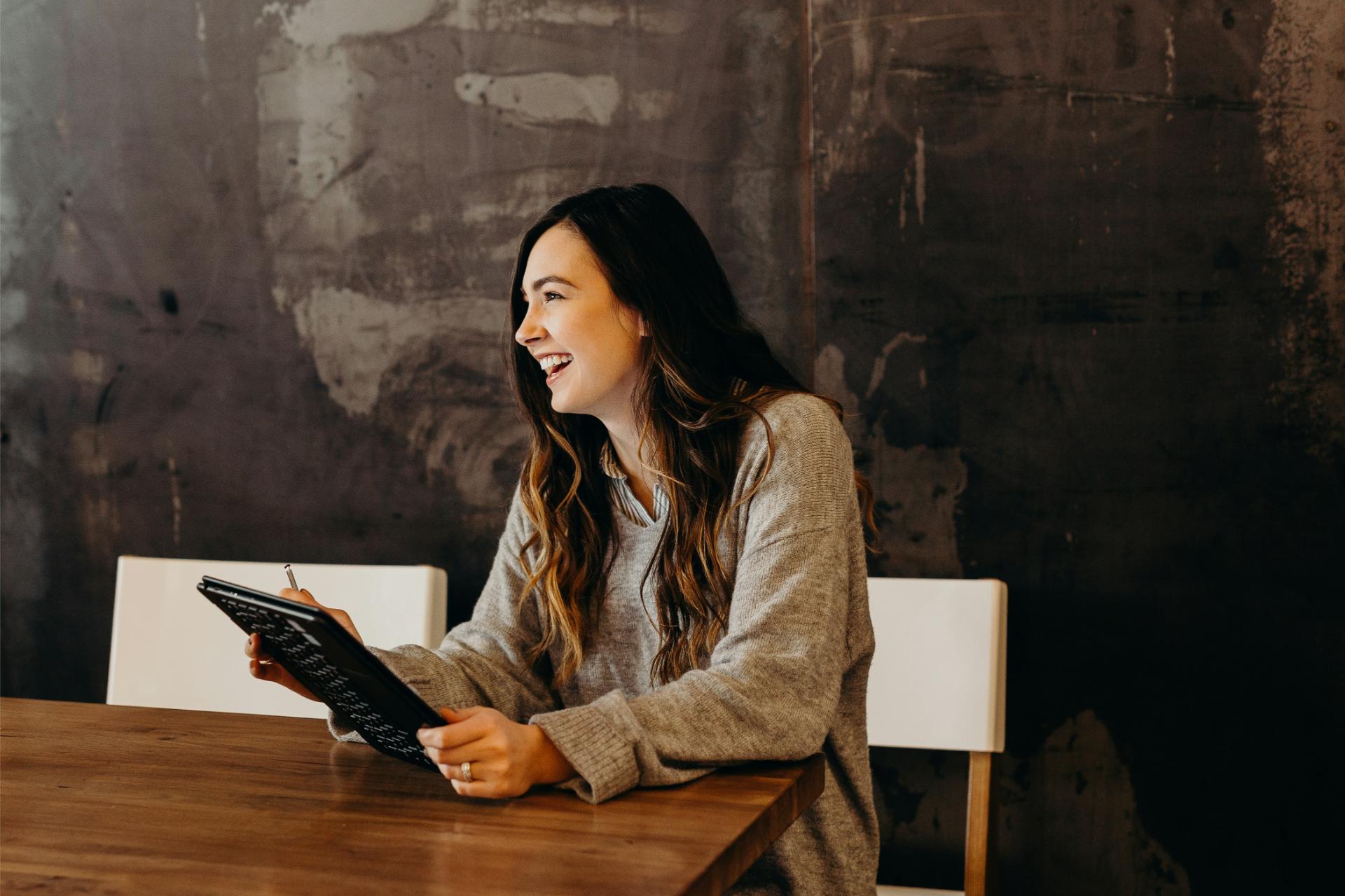 Woman laughing, holding a tablet