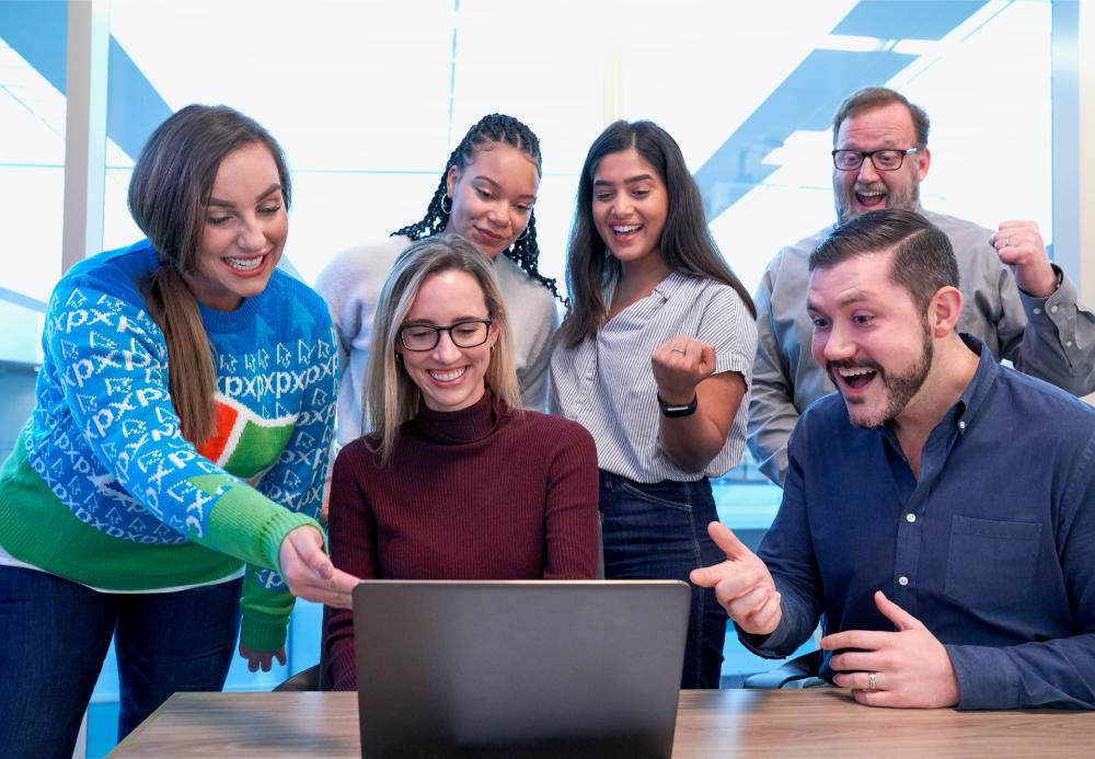 Group of coworkers excited around laptop