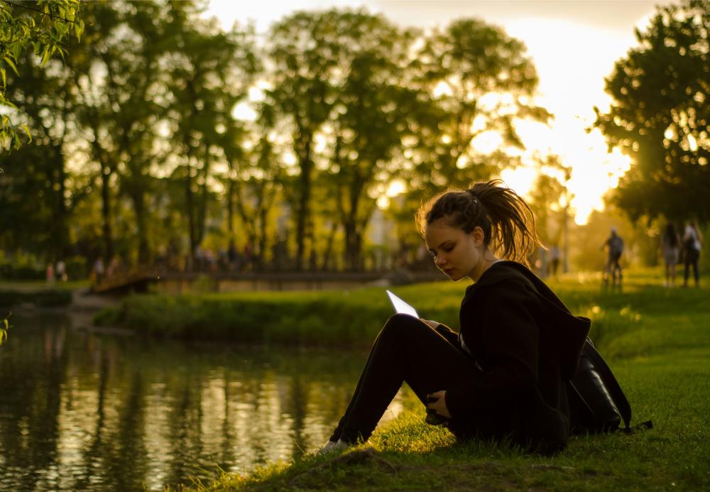 Girl reading by a peaceful pond