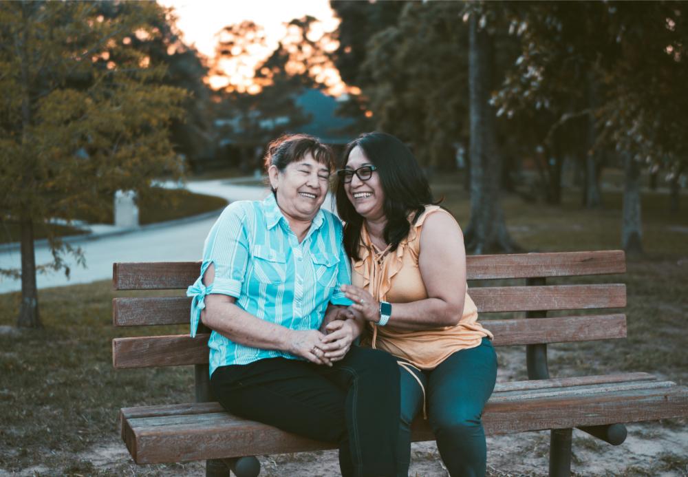 Two women smiling on park bench